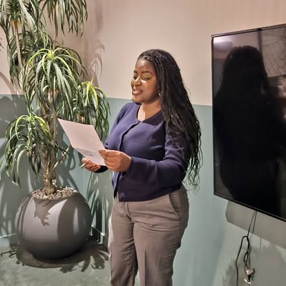 A club member speaking with a sheet of notes beside a plant